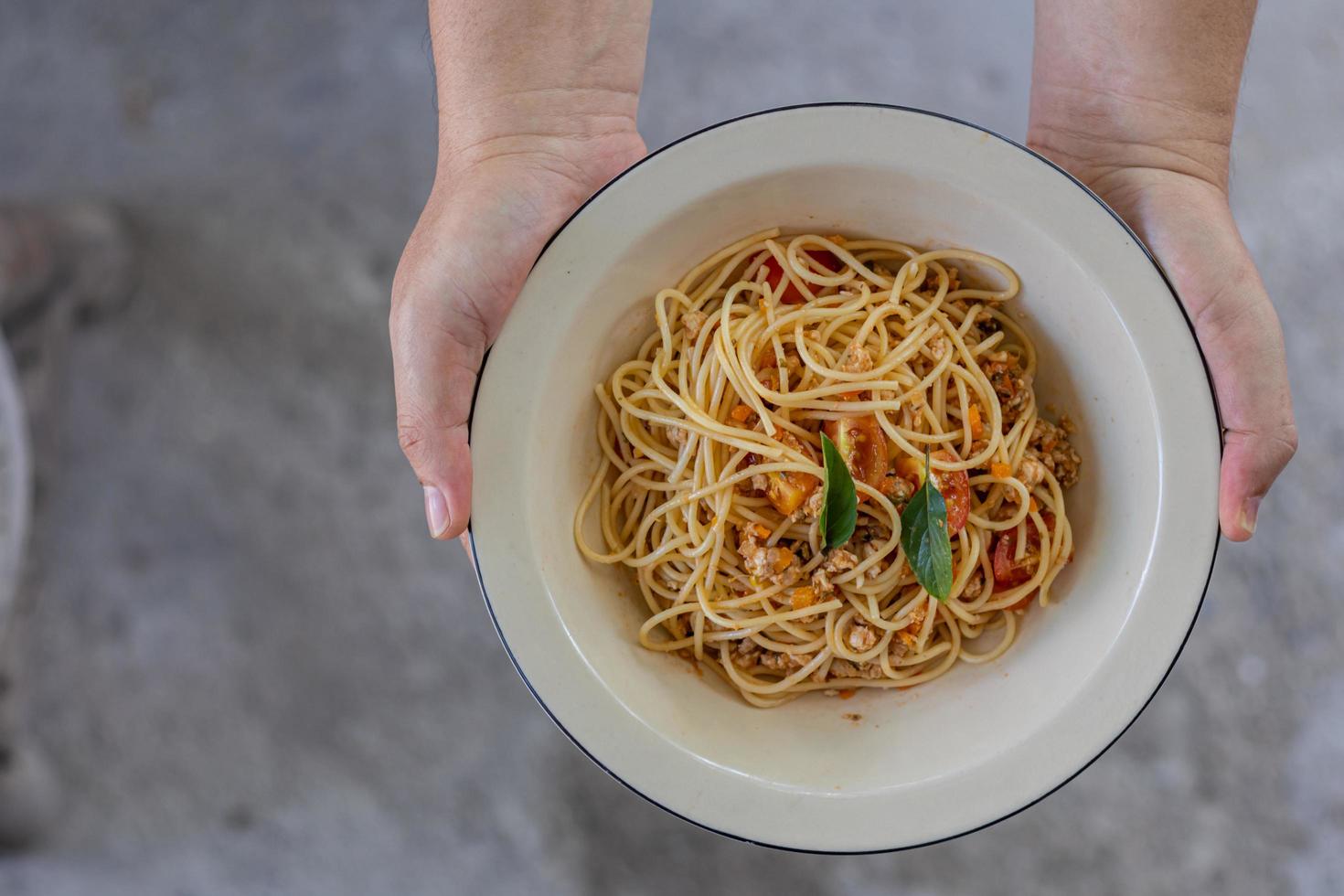 Spaghetti stir-fried with tomato sauce and minced chicken in hot Thai style. Tender and delicious served in a white plate placed on a wooden table, resulting in a delicious spaghetti from the sauce. photo