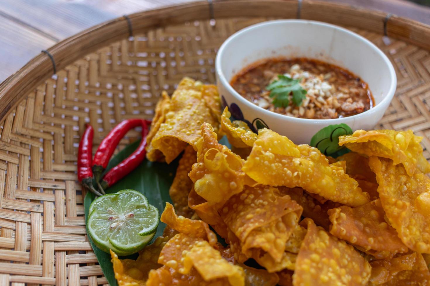 Crispy dumplings wrapped in chicken, vegetables and spices are served in a white plate placed on a wooden table inside the restaurant. Fried dumplings are popular for their delicious taste. photo