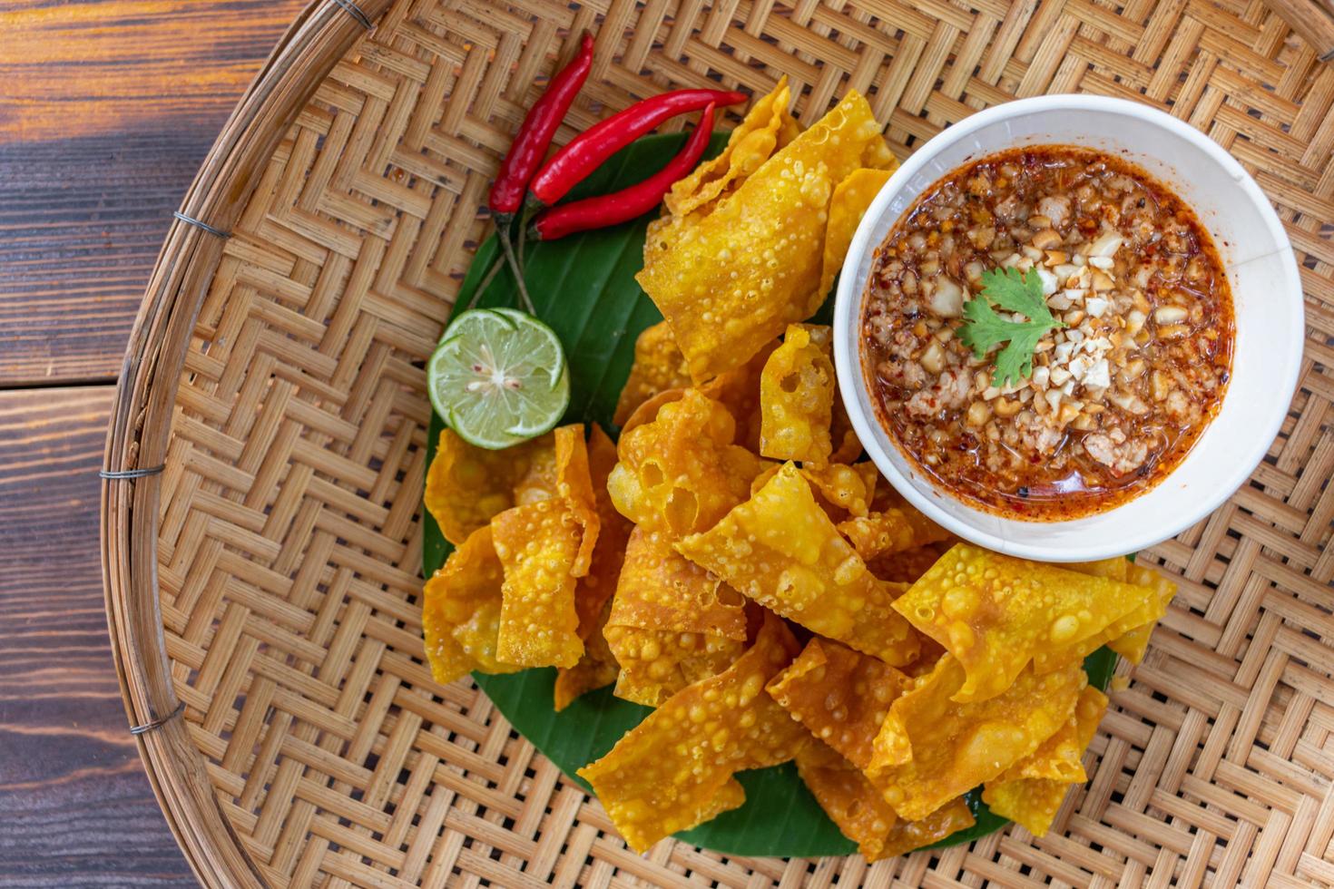 Crispy dumplings wrapped in chicken, vegetables and spices are served in a white plate placed on a wooden table inside the restaurant. Fried dumplings are popular for their delicious taste. photo