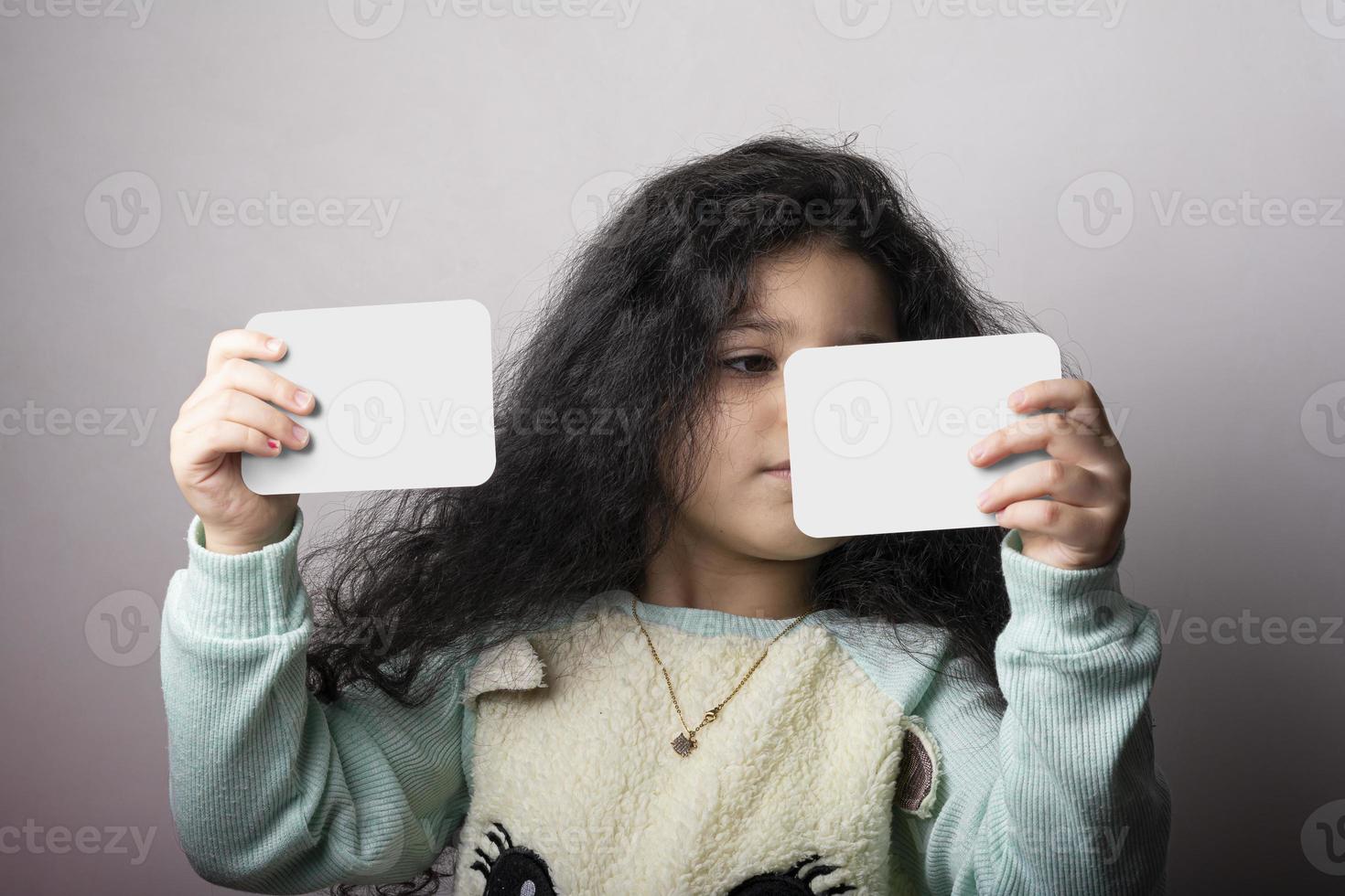 Little girl portrait holding two flash cards in hands mock-up series photo