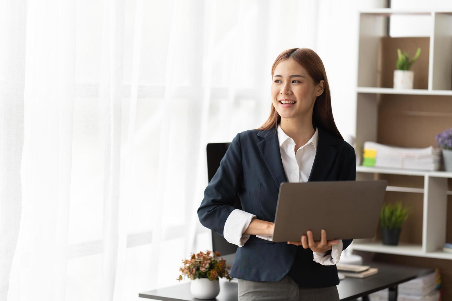 retrato de una mujer de negocios asiática feliz que trabaja en una computadora portátil con espacio para copiar. foto