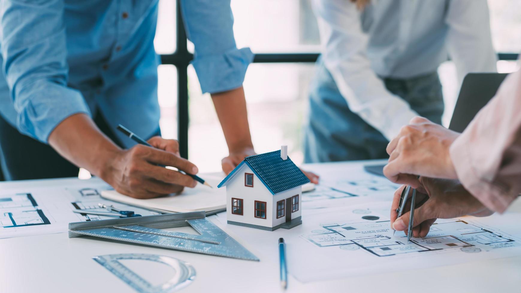 un grupo de arquitectos está diseñando un modelo de casa, ingenieros y arquitectos trabajando juntos para planificar un proyecto de construcción de casas. foto