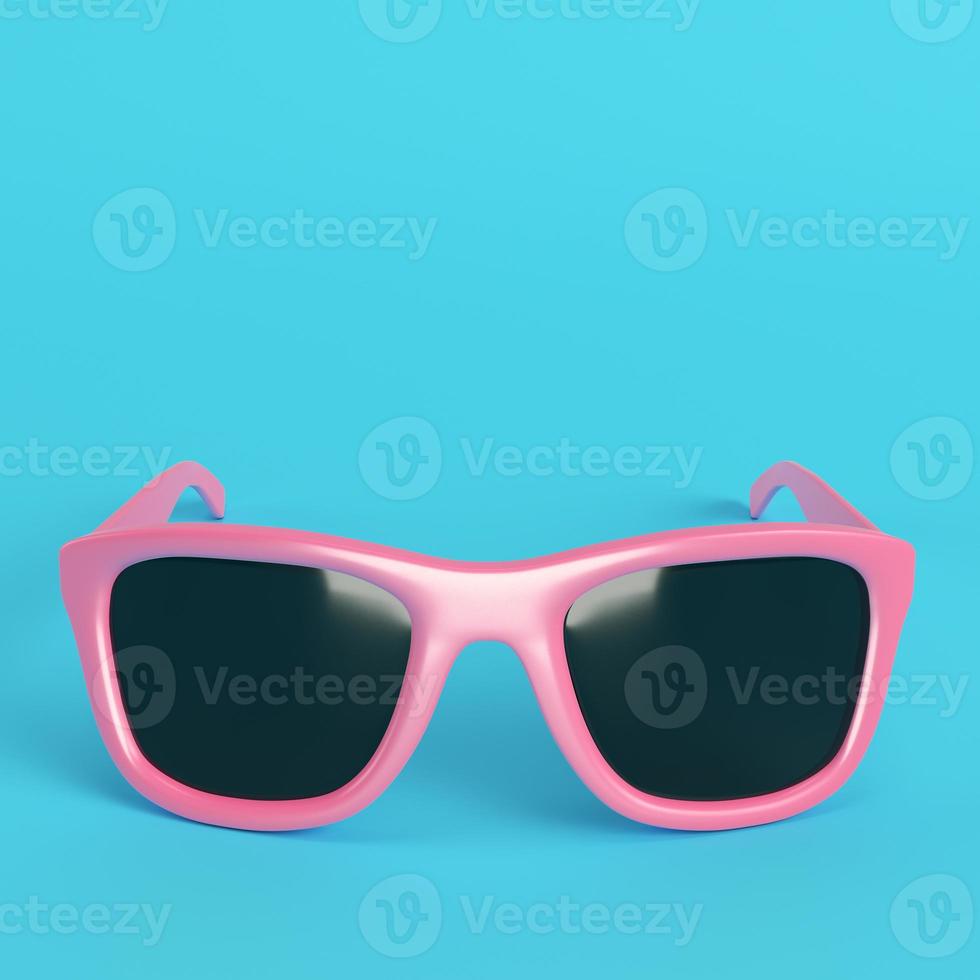 Pink sun glasses with black lenses on bright blue background in pastel colors photo