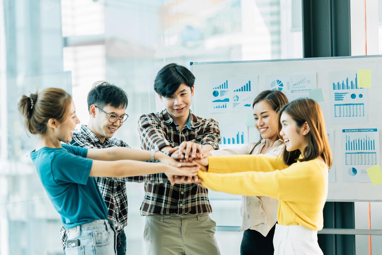 Happy successful asian business team giving a high fives gesture as they laugh and cheer their success. photo