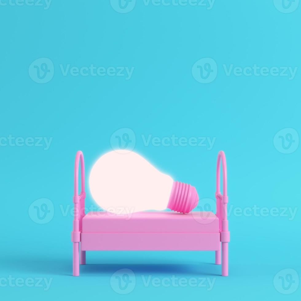 Pink single bed with glowing light bulb on bright blue background in pastel colors photo