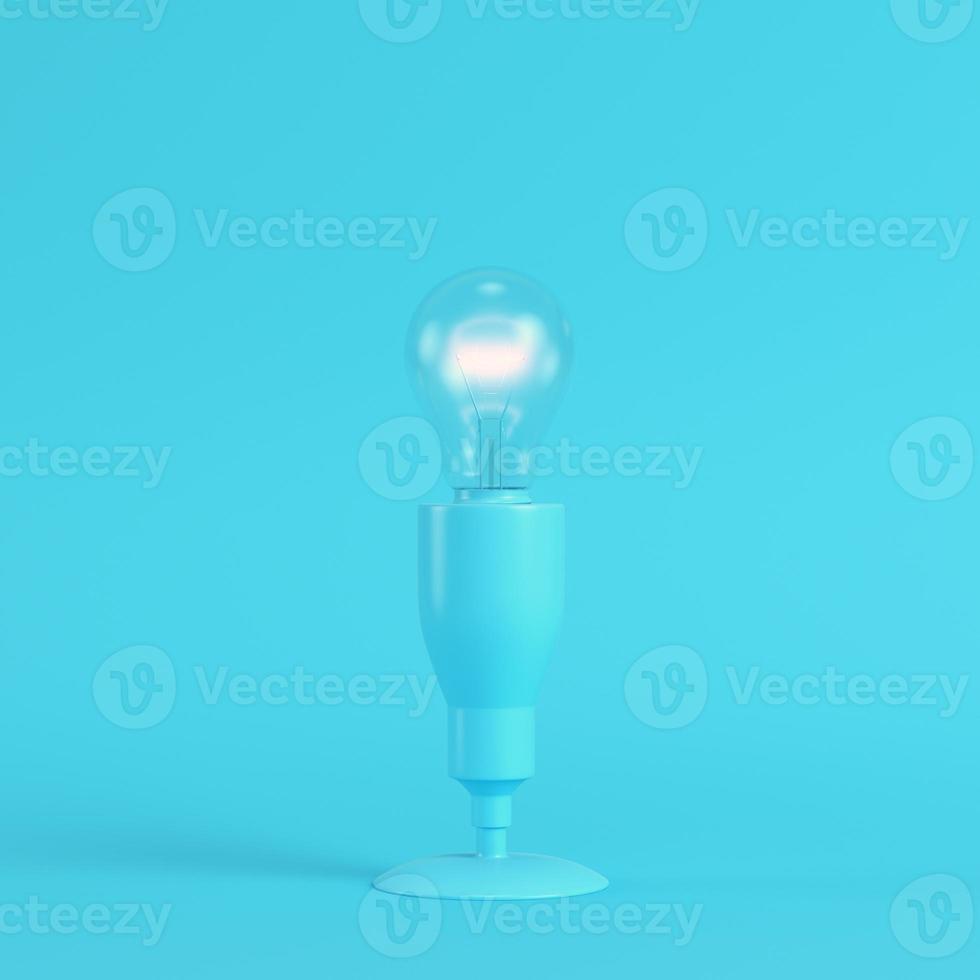 Lamp with glowing light bulb on bright blue background in pastel colors photo
