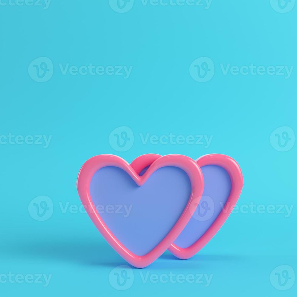 Two abstract pink hearts on bright blue background in pastel colors. photo