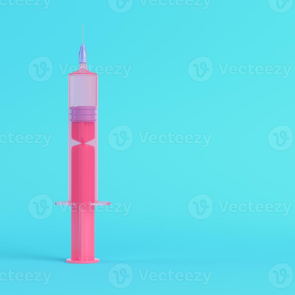 Pink syringe with vaccine on bright blue background in pastel colors photo