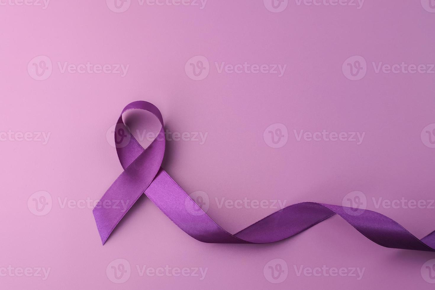 Purple ribbon as symbol of World Cancer Day over purple color background, copy space. photo