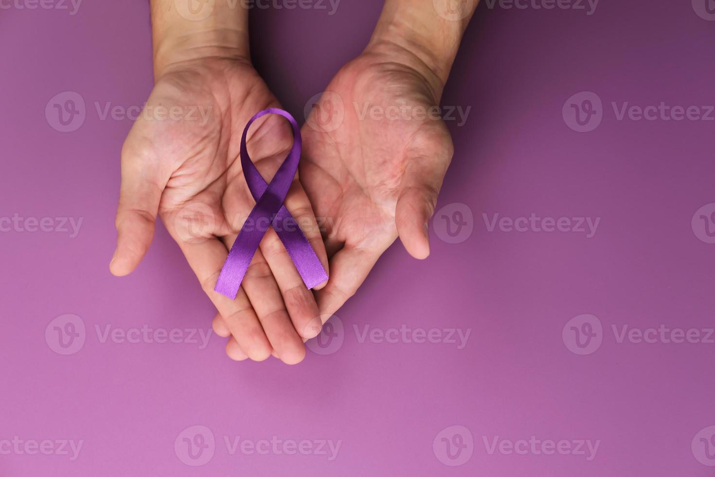 Purple ribbon as symbol of World Cancer Day over purple color background, copy space. photo