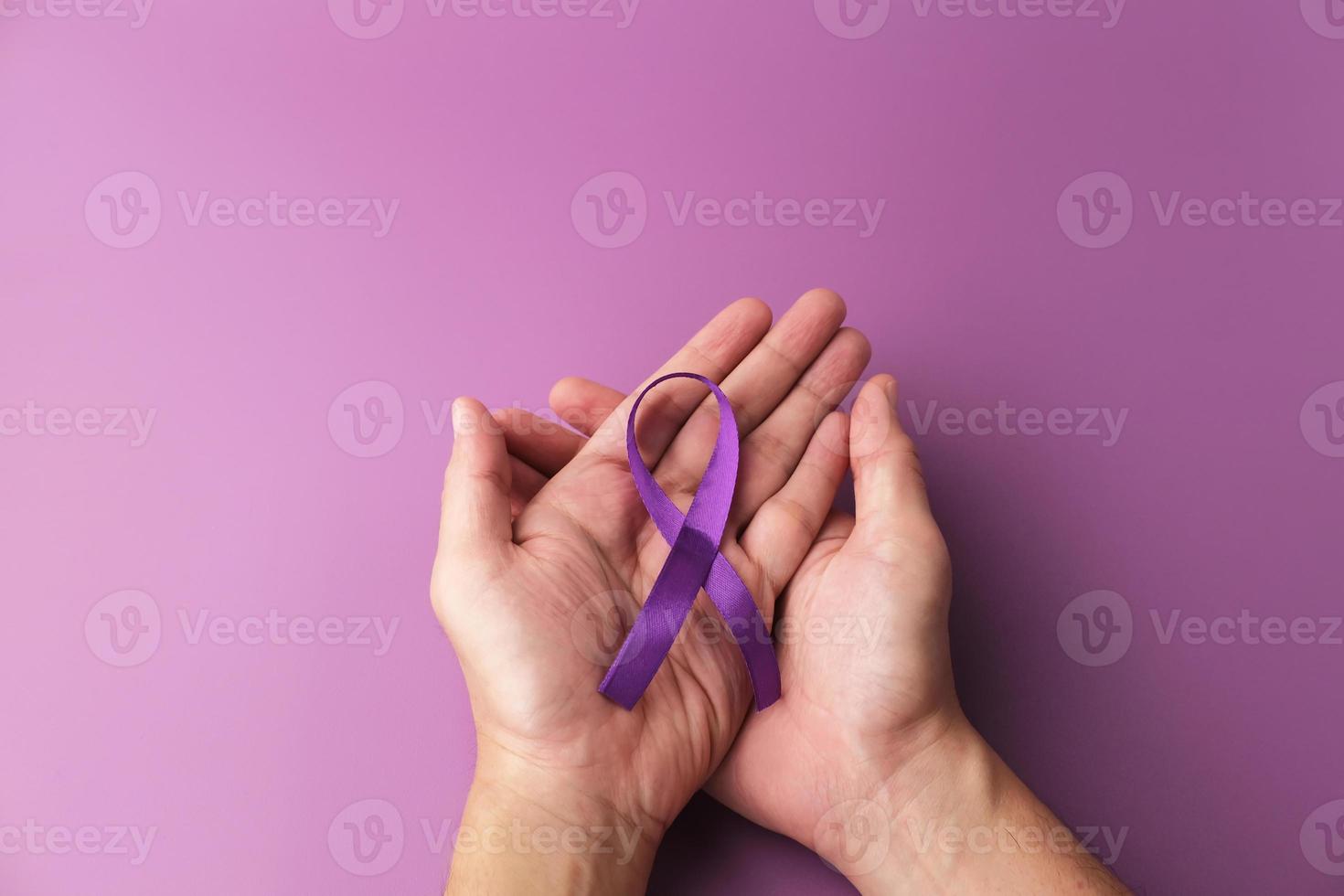 Purple ribbon as symbol of World Cancer Day over purple color background, copy space. photo