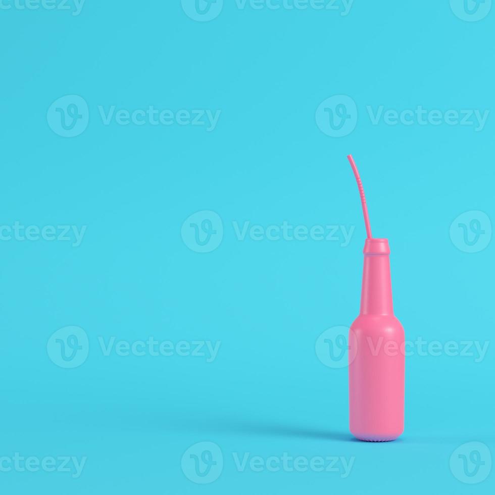 Pink bottle with straw on bright blue background in pastel colors photo
