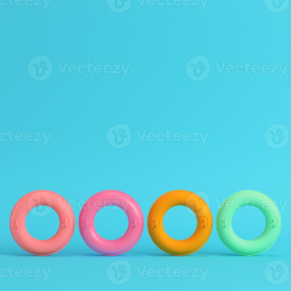 Four colorful inflatable rings on bright blue background in pastel colors photo