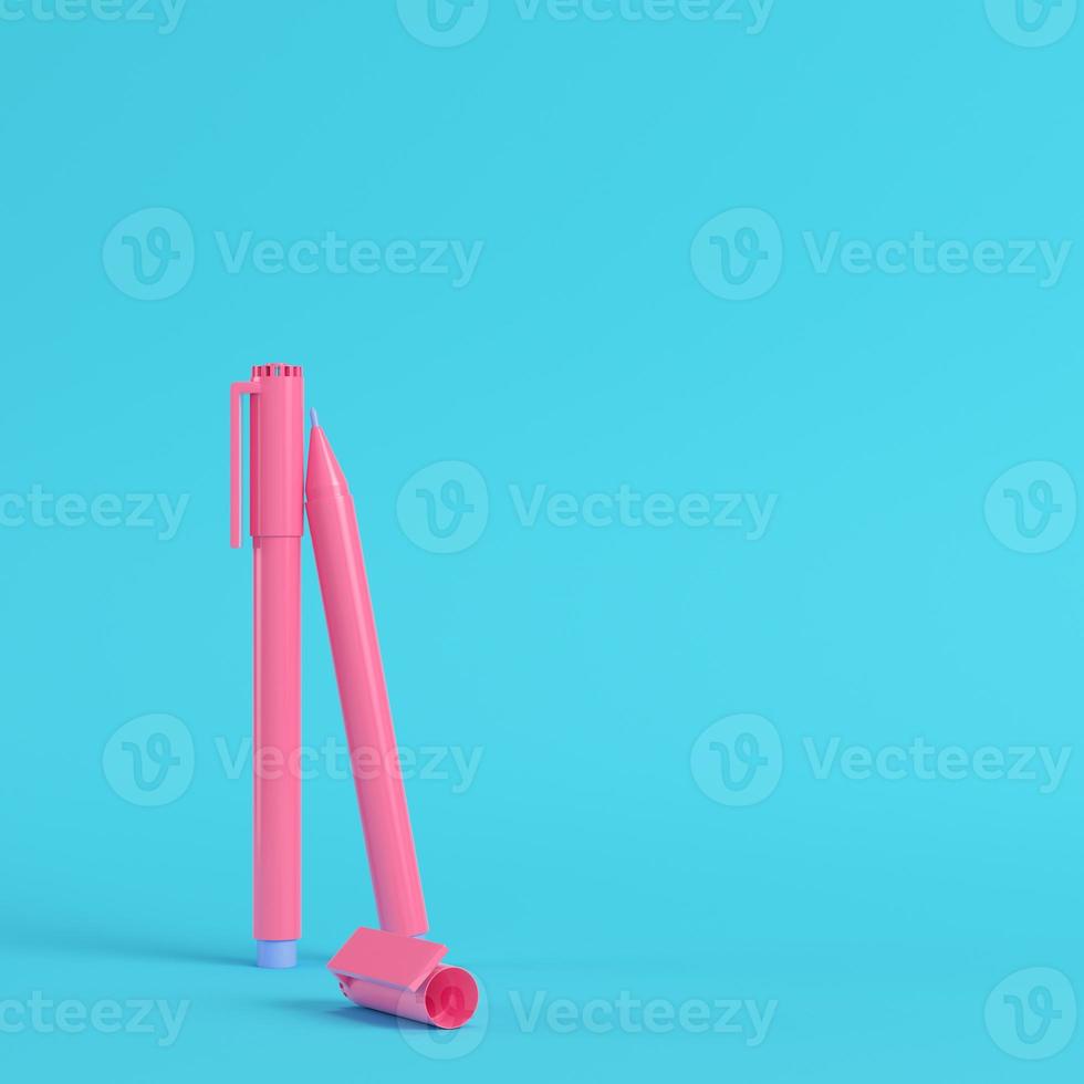 Pink marker pens on bright blue background in pastel colors. Minimalism concept photo