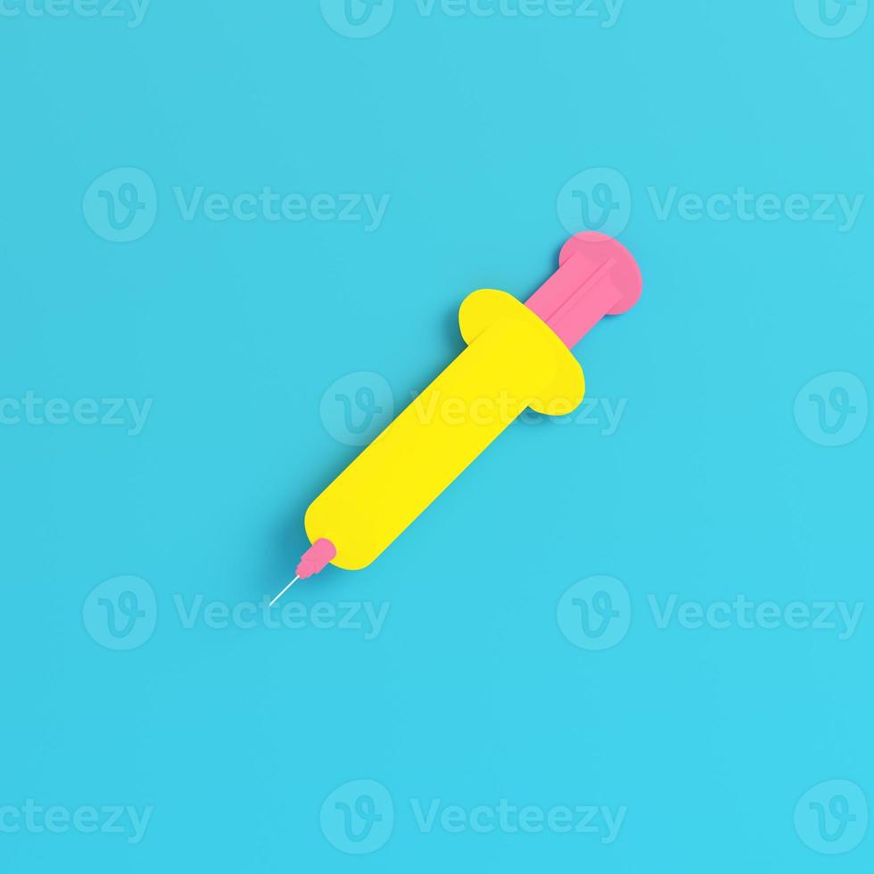 Yellow syringe on bright blue background in pastel colors photo