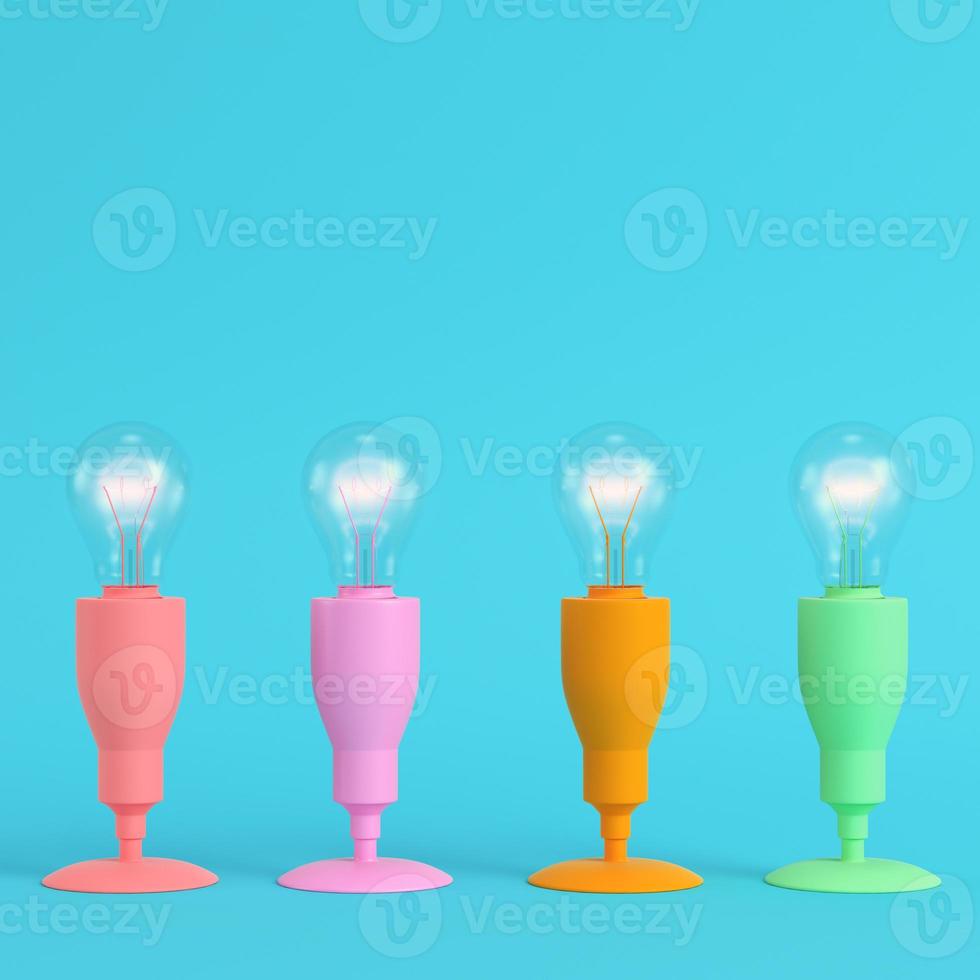 Four colorful lamps with glowing light bulb on bright blue background in pastel colors photo