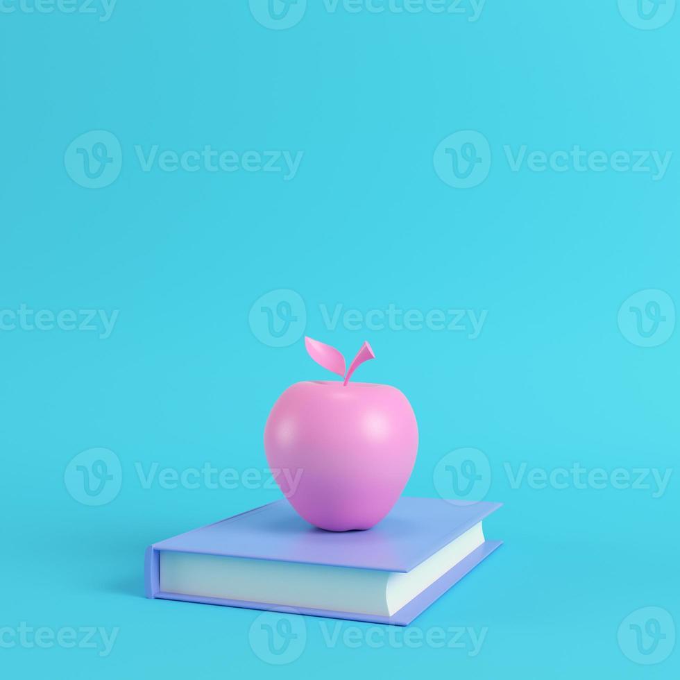 Pink apple on a book on bright blue background in pastel colors photo