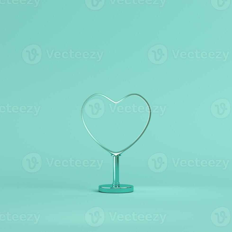 Metal heart shape with stand on bright green background in pastel colors photo