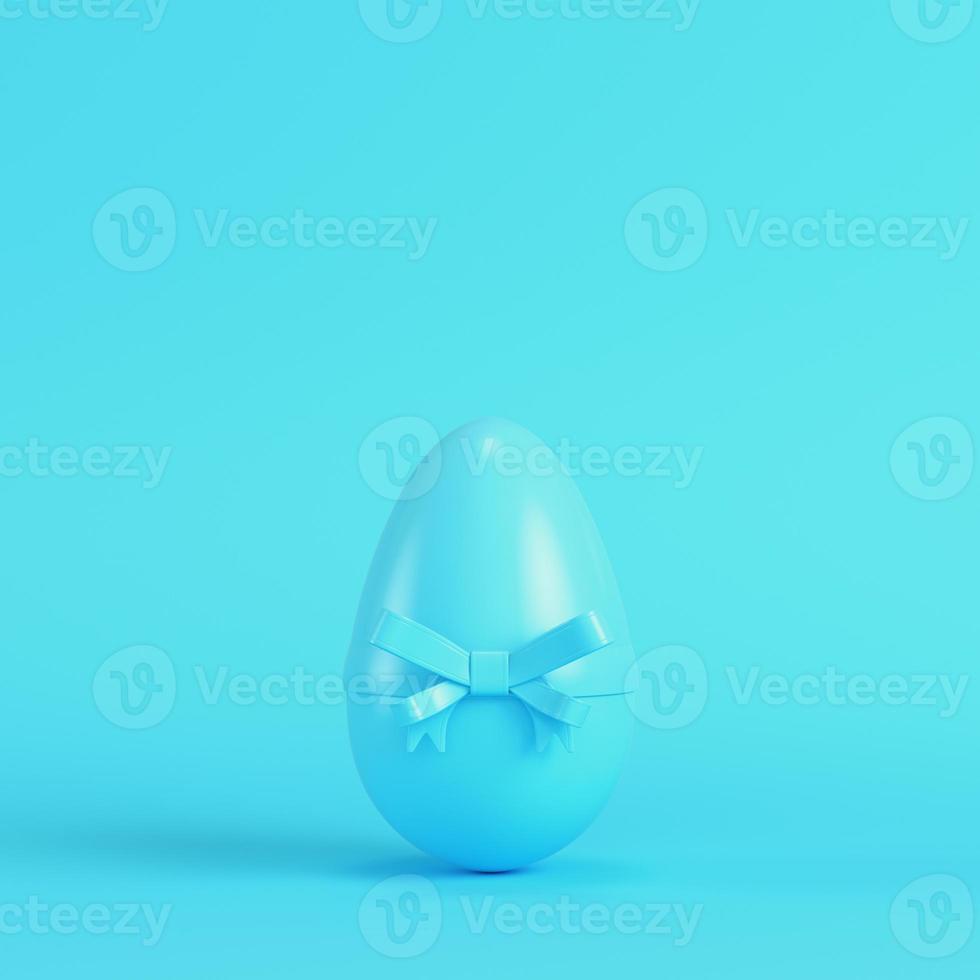 Easter egg with bow on bright blue background in pastel colors photo