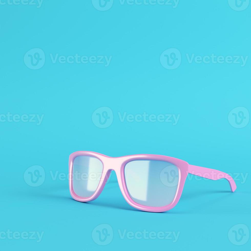 Pink sun glasses on bright blue background in pastel colors photo