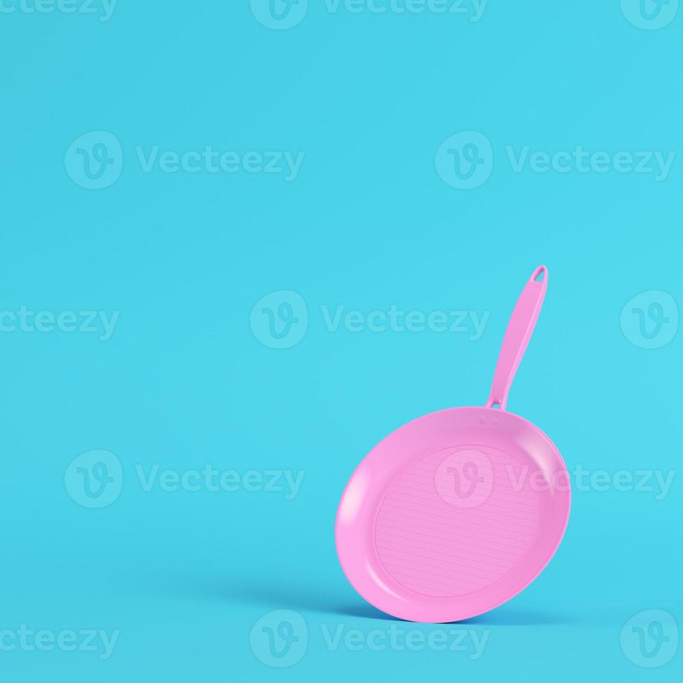 Pink frying pan on bright blue background in pastel colors photo