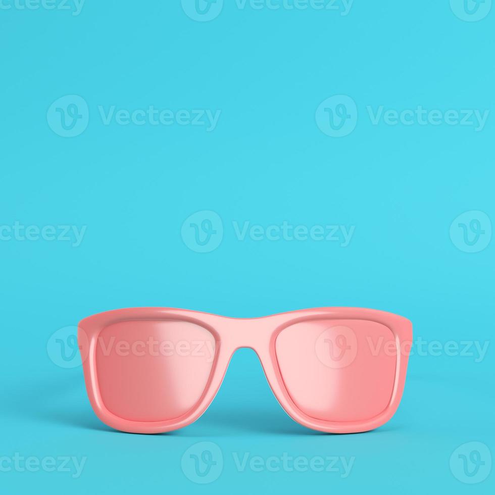 Red sun glasses on bright blue background in pastel colors with copy space photo