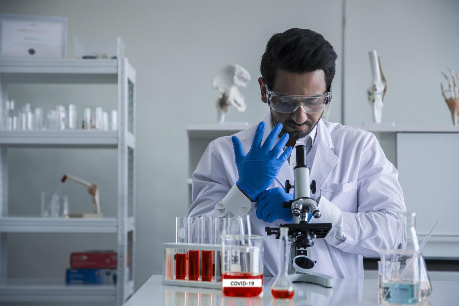 trabajador médico científico atractivo con tubo de ensayo de muestra en el laboratorio, haciendo un análisis en un laboratorio investigando para crear una vacuna y desarrollo foto