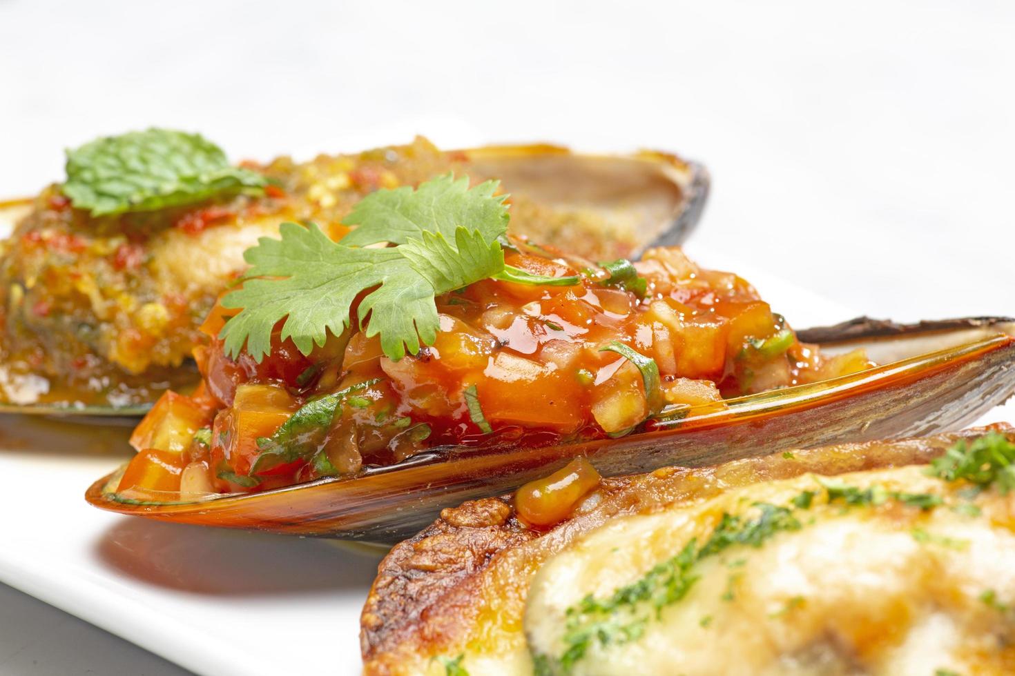 close-up of baked mussels with cheese on a plate and white background. soft focus. shallow focus effect. photo