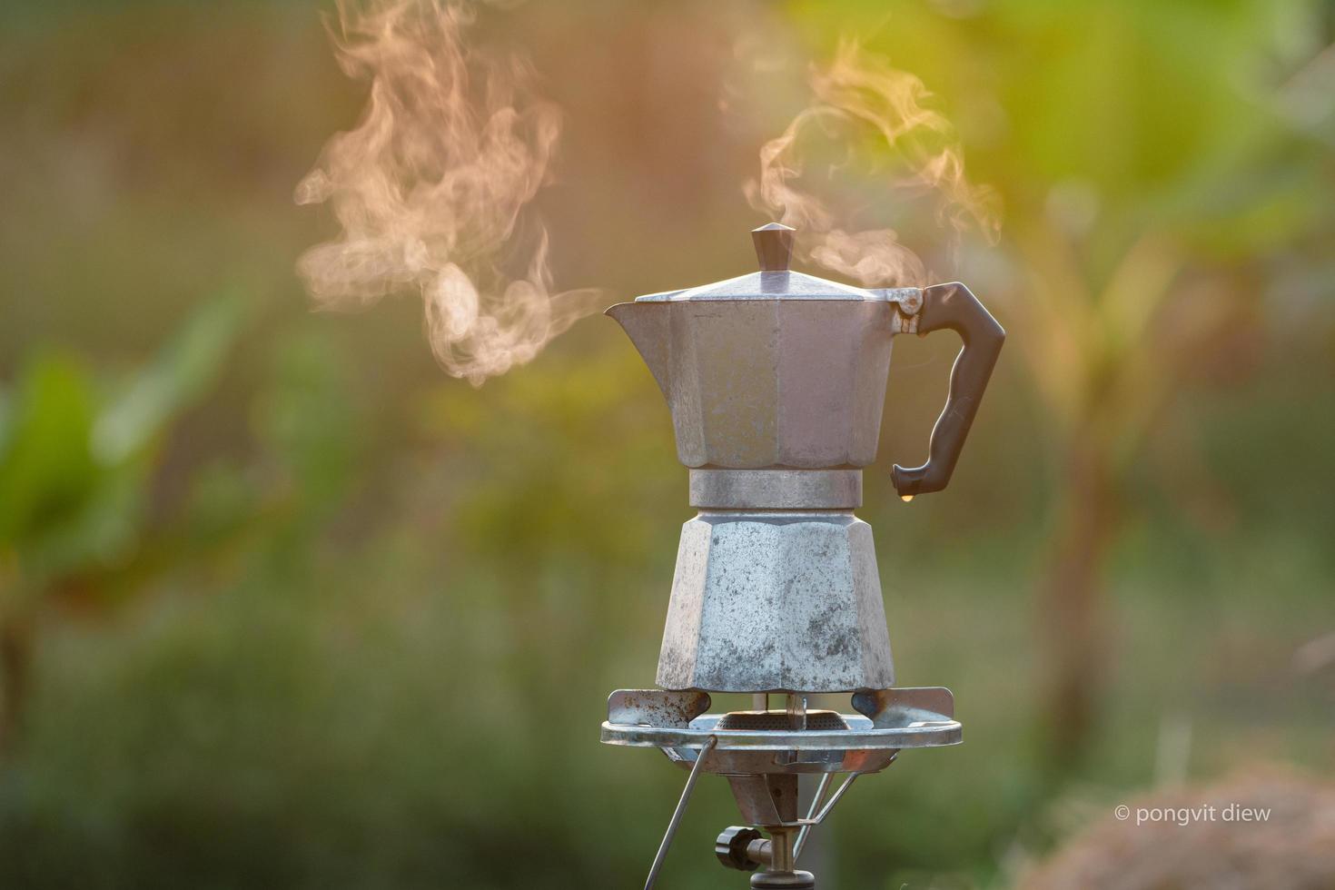 cafetera moka antigua en la estufa de gas para acampar cuando sale el sol por la mañana. enfoque suave. foto