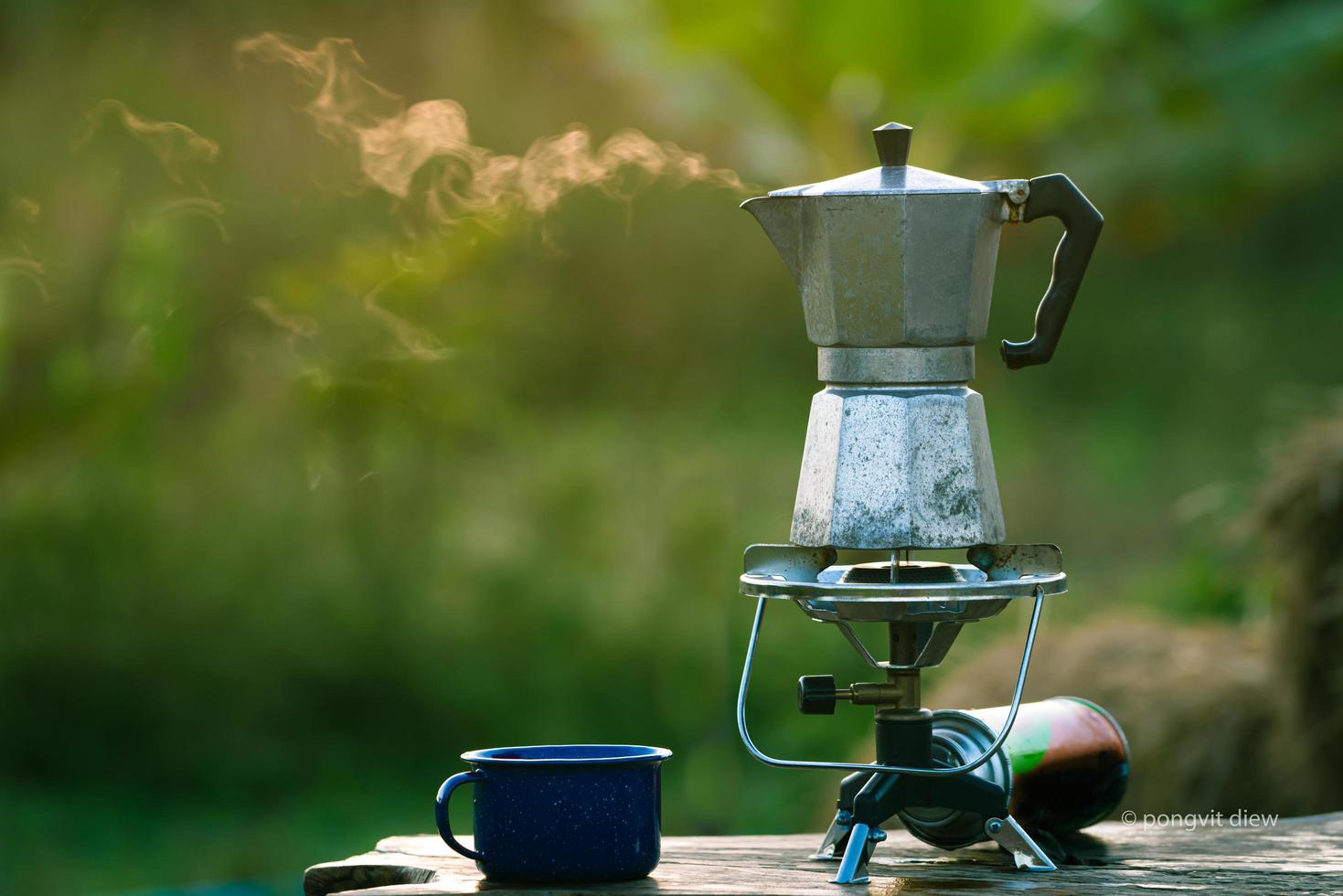 cafetera moka antigua en la estufa de gas para acampar cuando sale el sol por la mañana. enfoque suave. foto