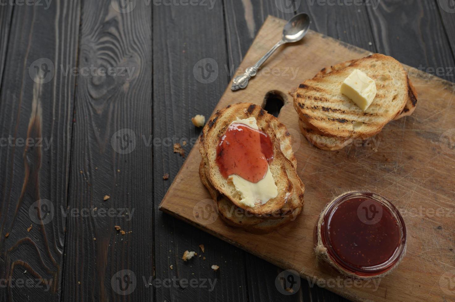 Toast bread with homemade strawberry jam and on rustic table with butter for breakfast or brunch. photo