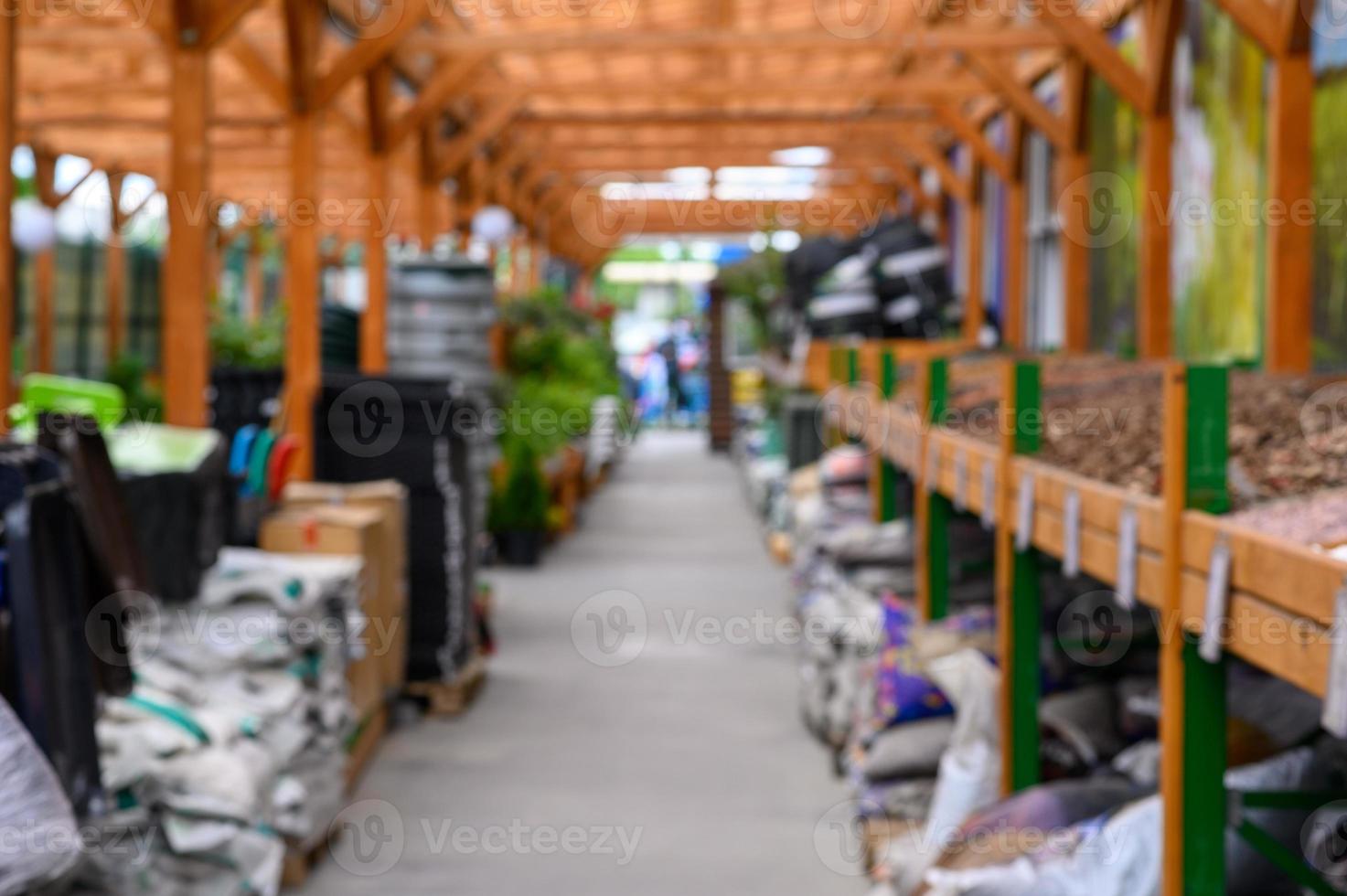 Shop of garden equipment. Lawn mowers. Defocused image. In the foreground is the top of a wooden table or counter. photo