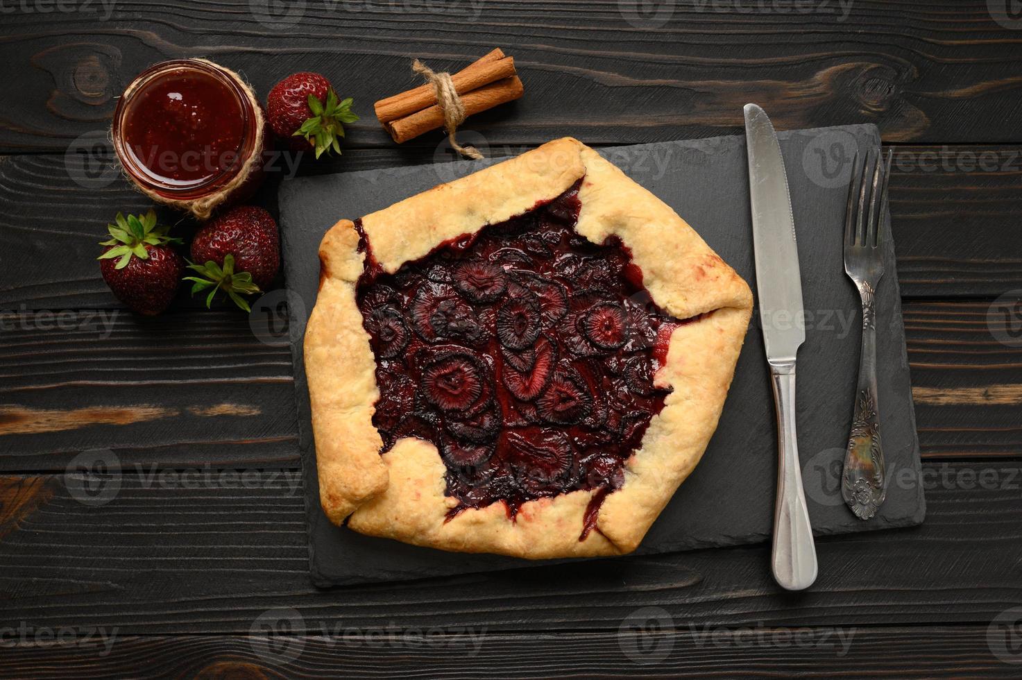 Strawberry galette on dark wooden background. Homemade photo