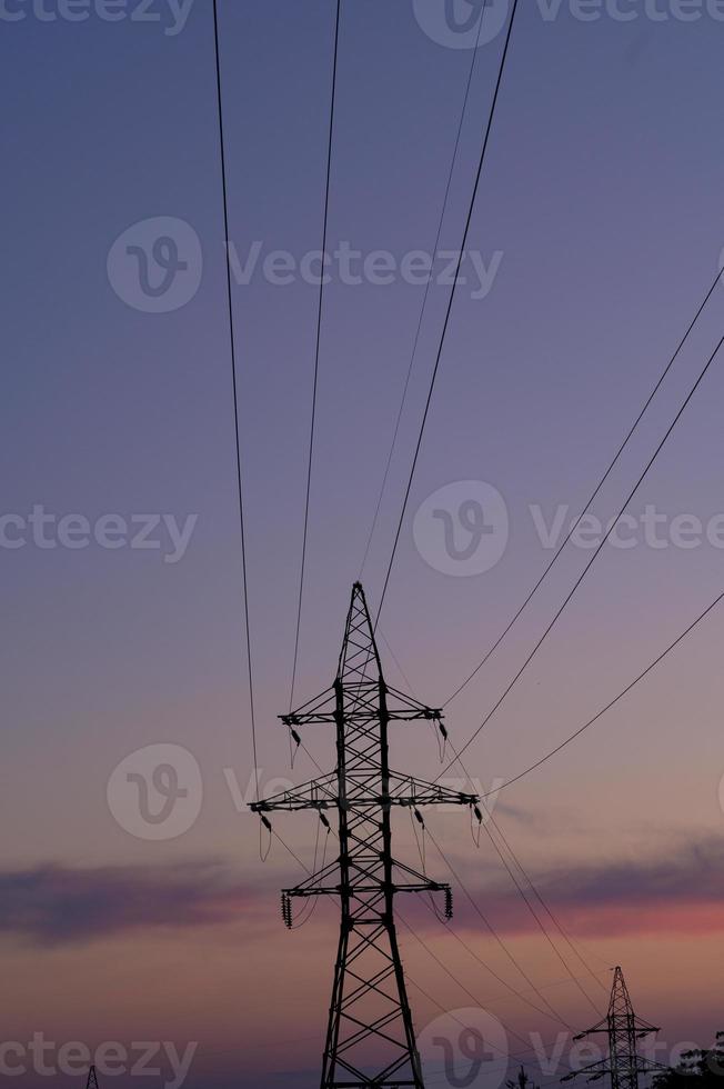 Close up high voltage power lines station. High voltage electric transmission pylon silhouetted tower. photo