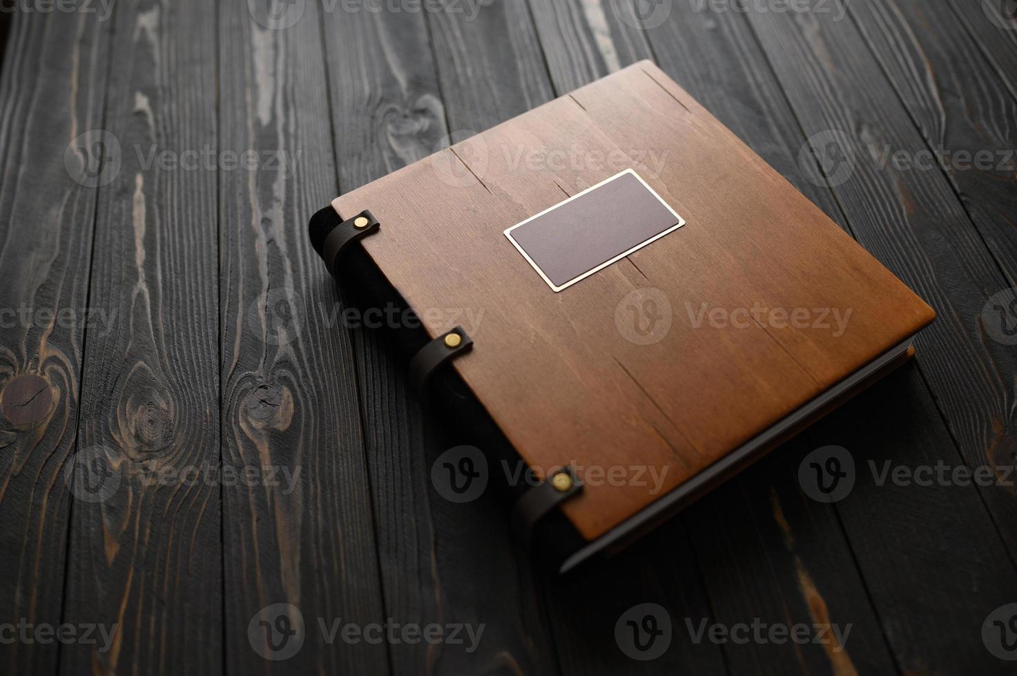 An old photo album with a wooden cover and a shield on a rustic table. free logo