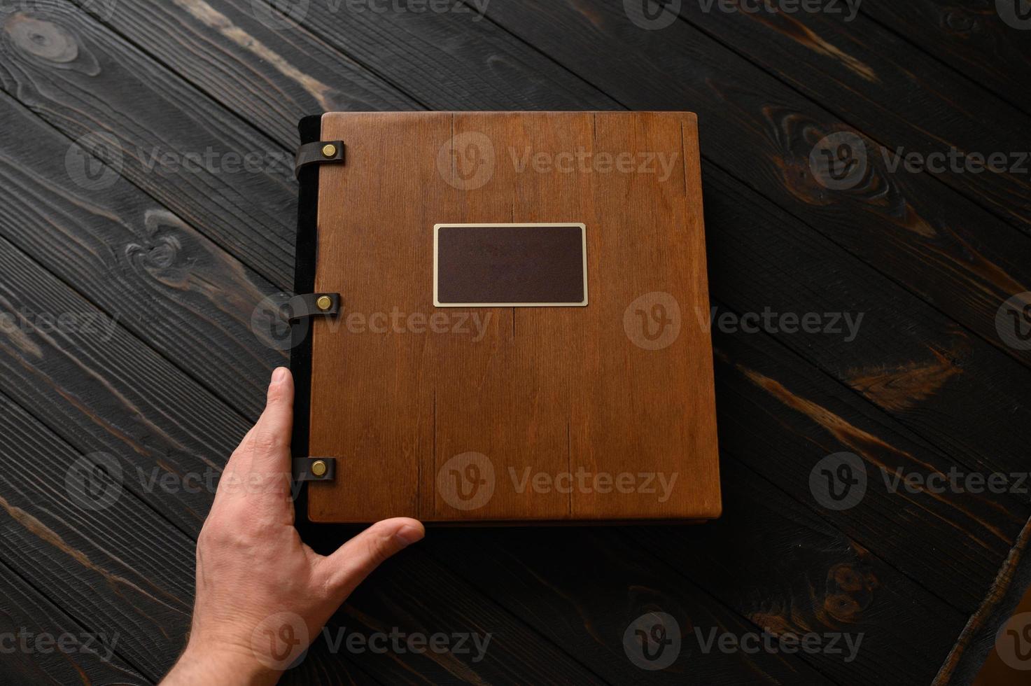 An old photo album with a wooden cover and a shield on a rustic table. free logo