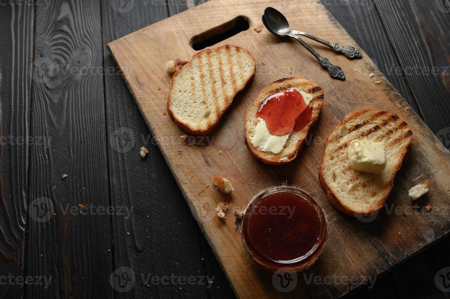 Toast bread with homemade strawberry jam and on rustic table with butter for breakfast or brunch. photo