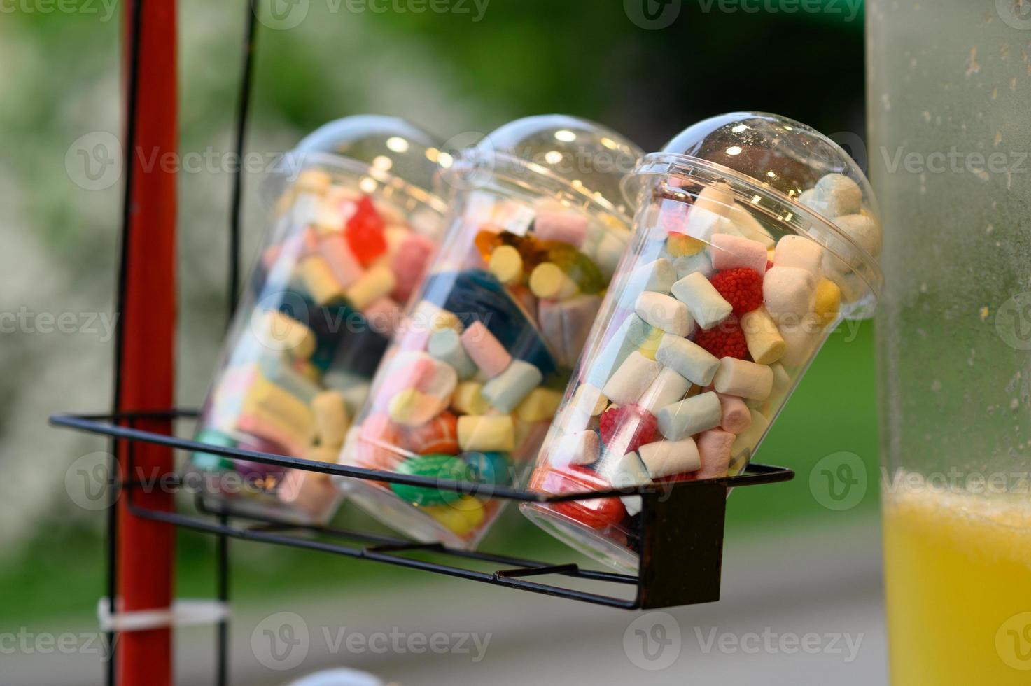 A variety of jelly candies are packed in plastic cups. photo