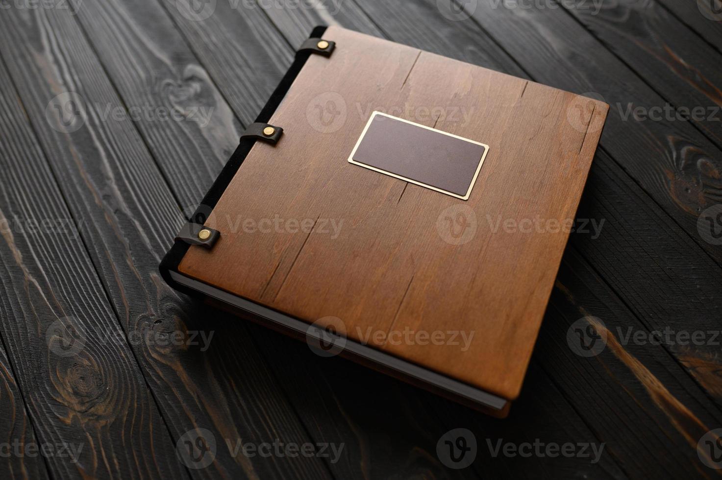 An old photo album with a wooden cover and a shield on a rustic table. free logo