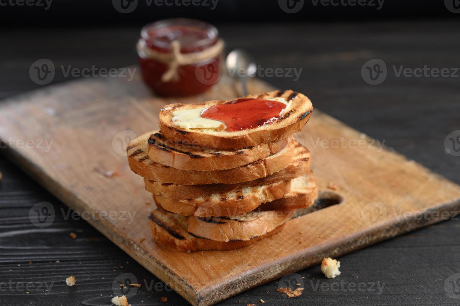 Toast bread with homemade strawberry jam and on rustic table with butter for breakfast or brunch. photo