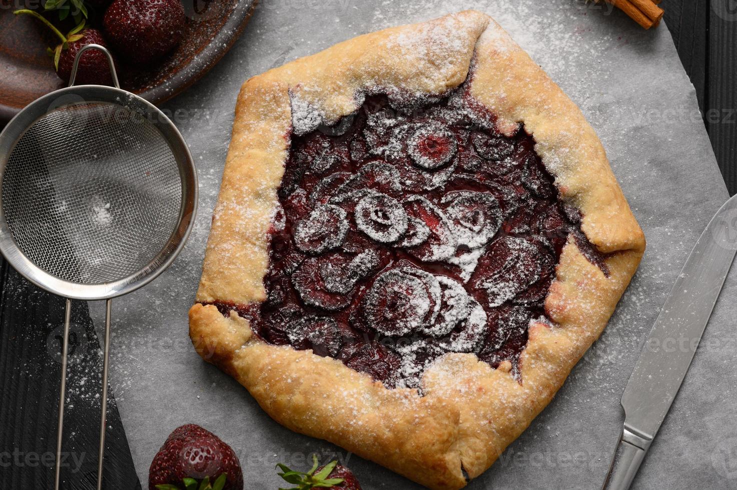 Strawberry galette on dark wooden background. Homemade photo