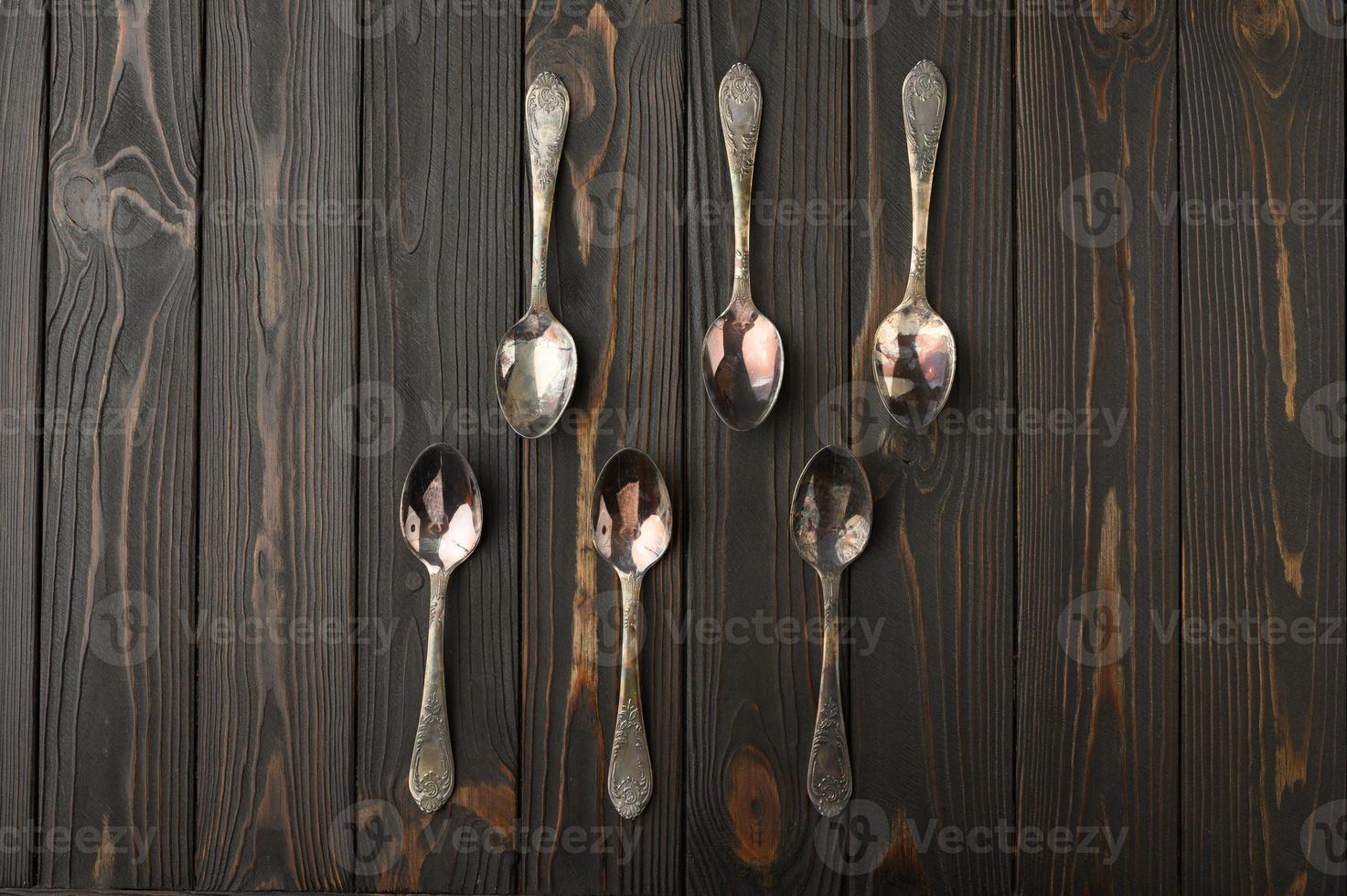 Six old silver spoons on a rustic wooden background. photo