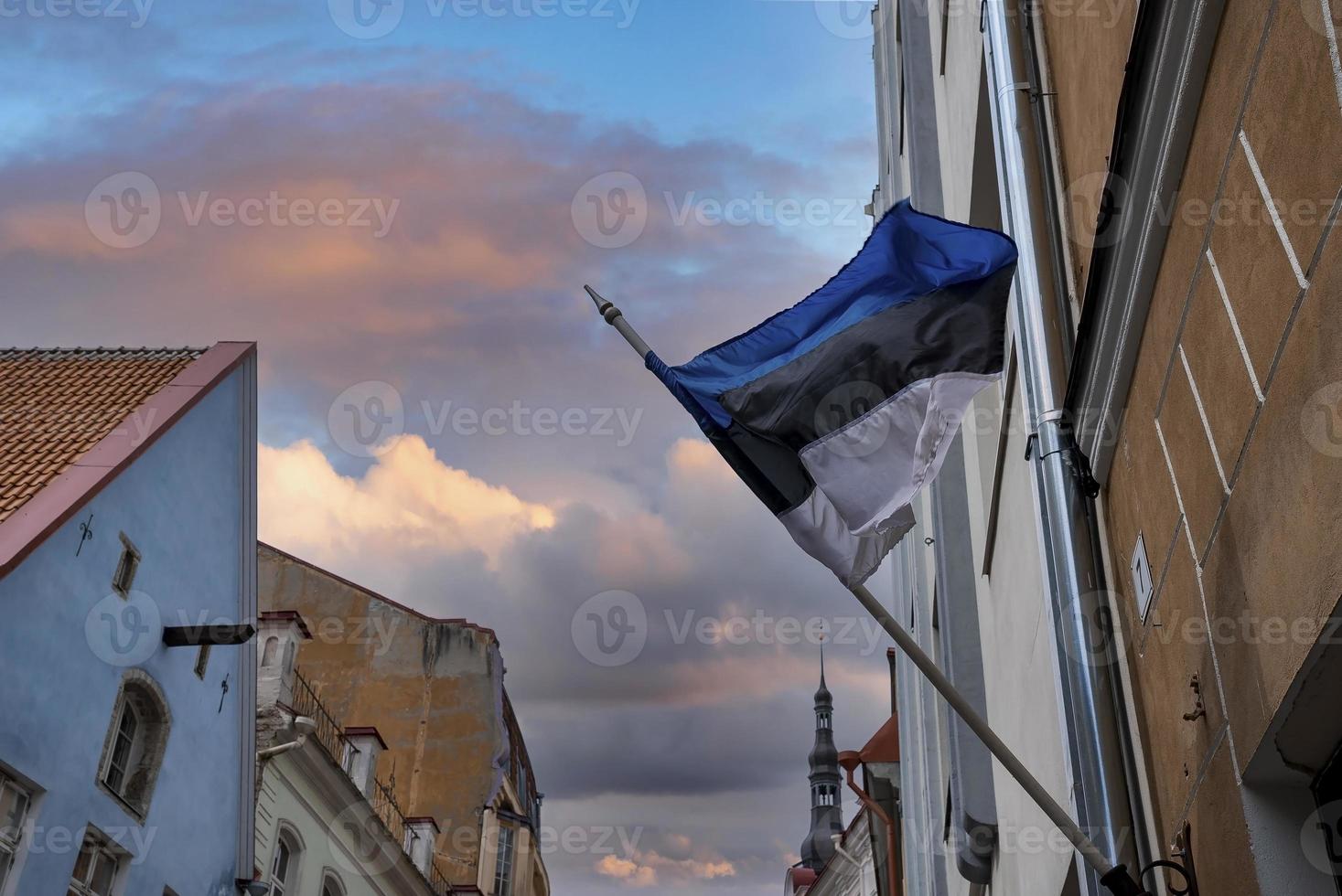 Low angle view of Estonian flag waving against buildings in town during sunset photo