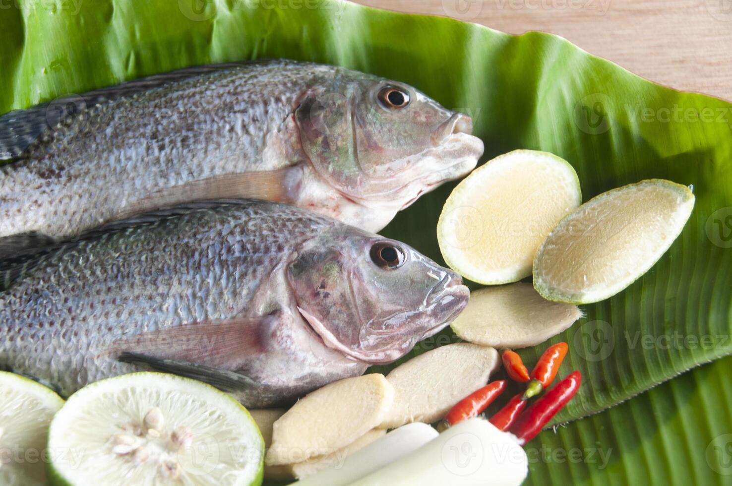 To view of fresh tilapia fish with lemongrass, lemon and chili on banana leaf. photo