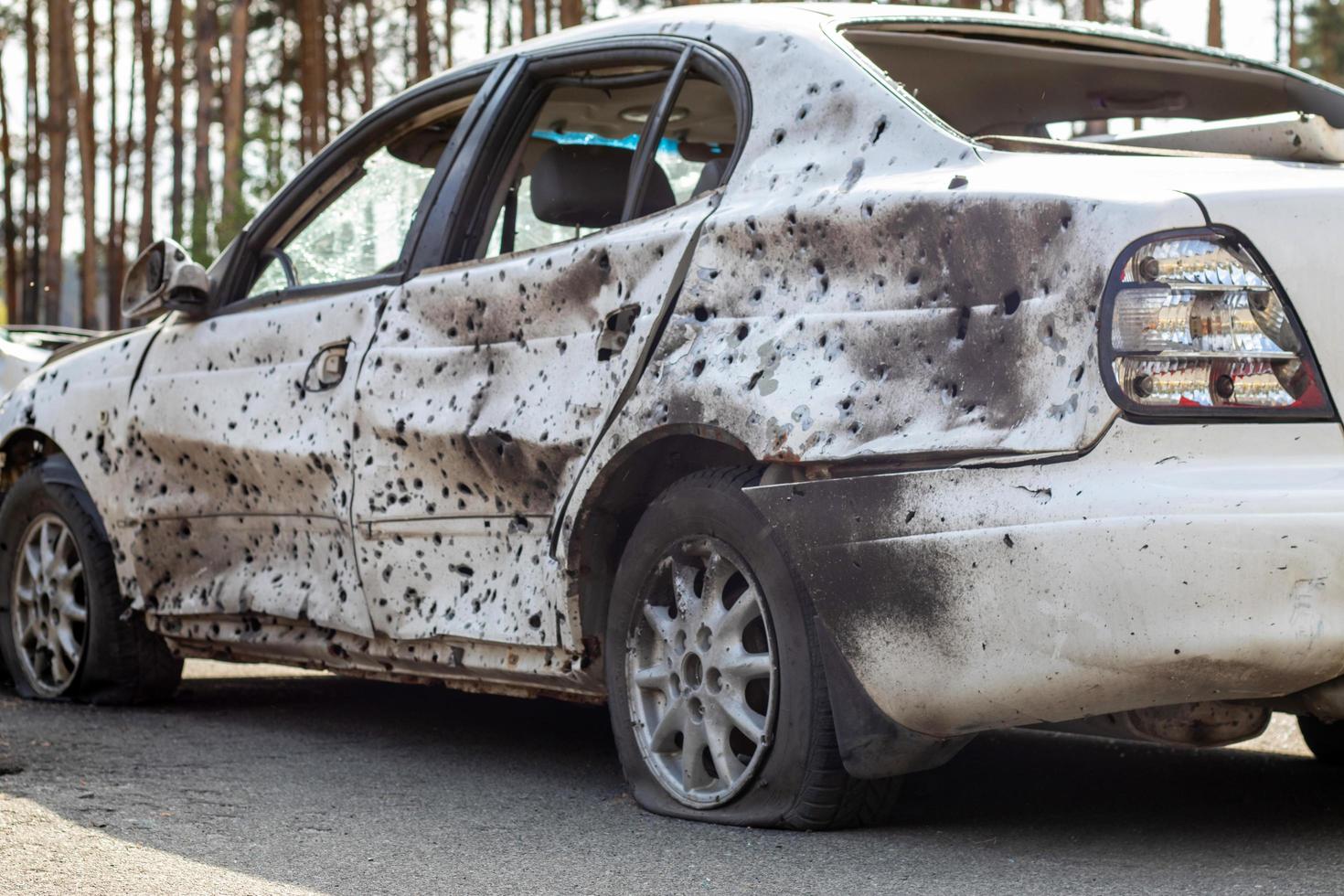 Shot, damaged cars during the war in Ukraine. The vehicle of civilians affected by the hands of the Russian military. Shrapnel and bullet holes in the body of the car. Ukraine, Irpen - May 12, 2022. photo