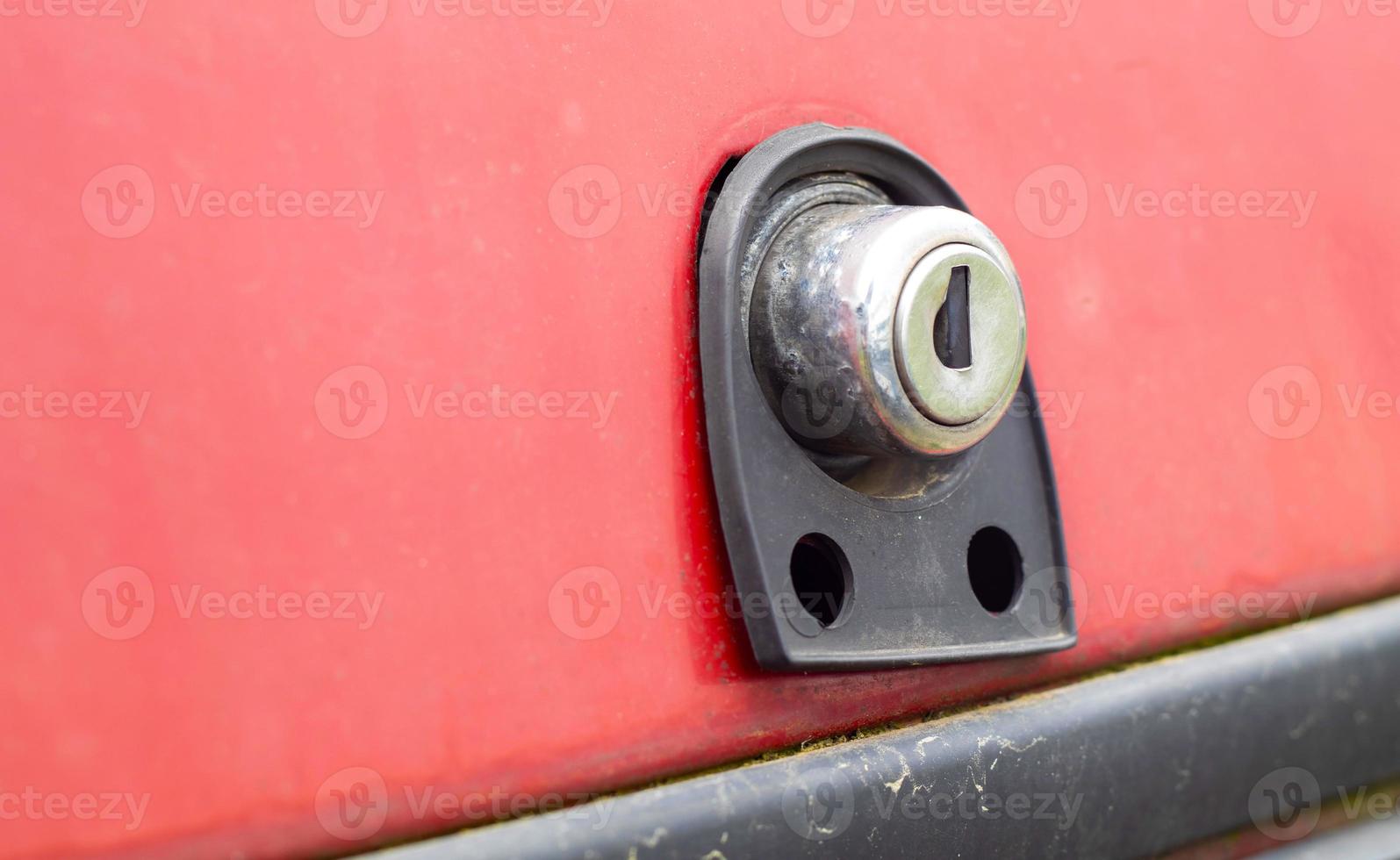 Old car trunk lock. Trunk lock details. Close-up of a handle to open the back door of a vintage red car. photo