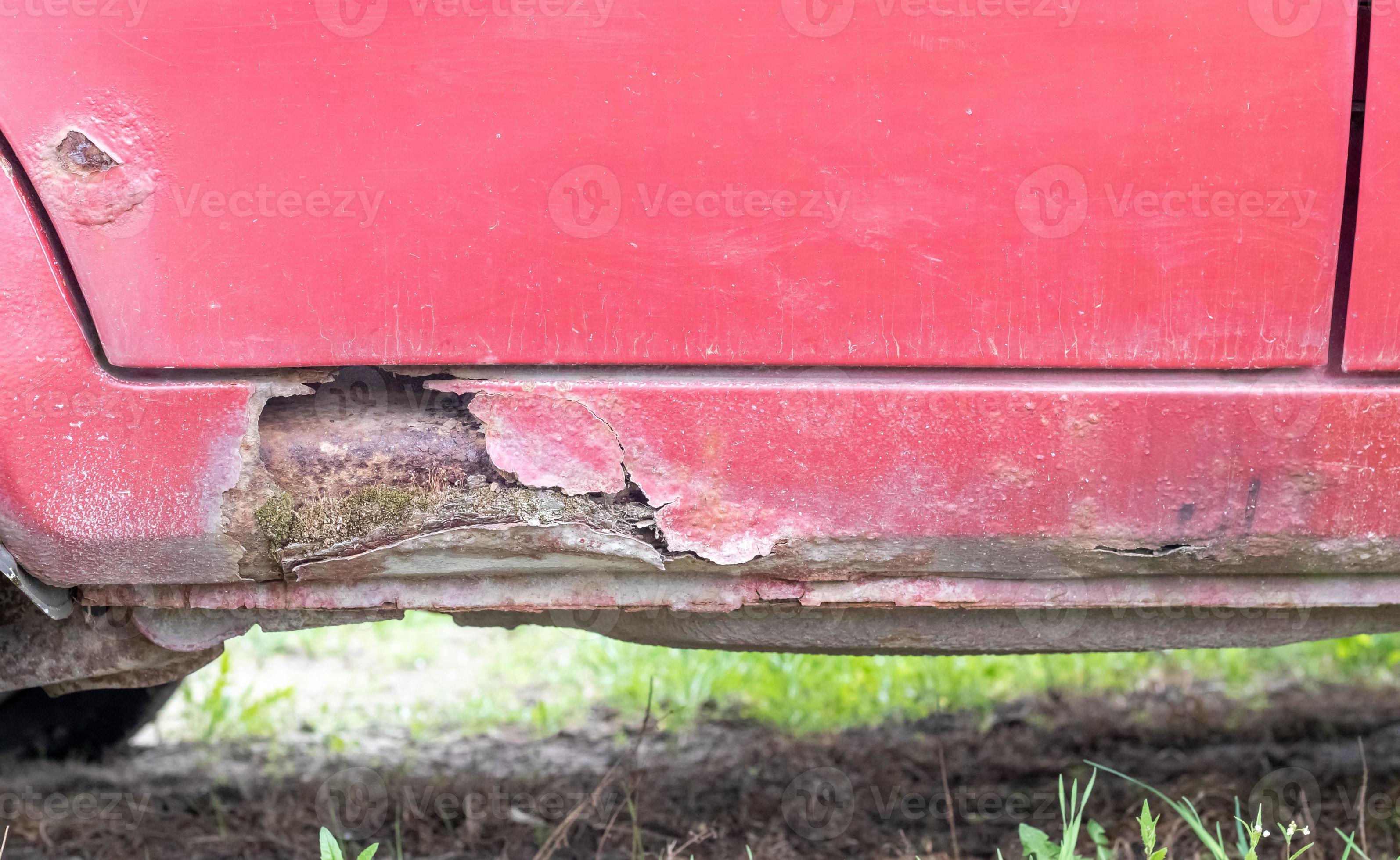 Rusty driver's door sills. Corrosion of the body of a red old car after