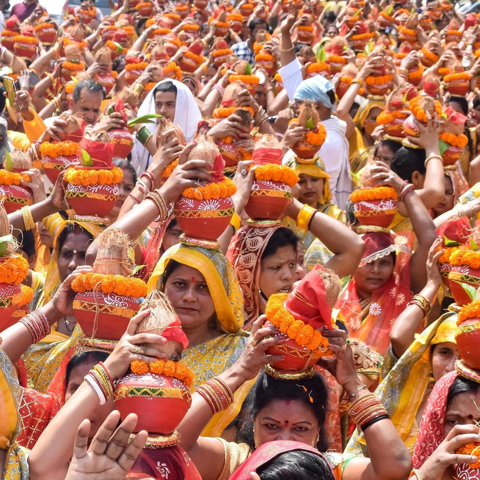 nueva delhi, india 03 de abril de 2022 - mujeres con kalash en la cabeza durante el templo jagannath mangal kalash yatra, devotos hindúes indios llevan ollas de barro que contienen agua sagrada con un coco encima foto