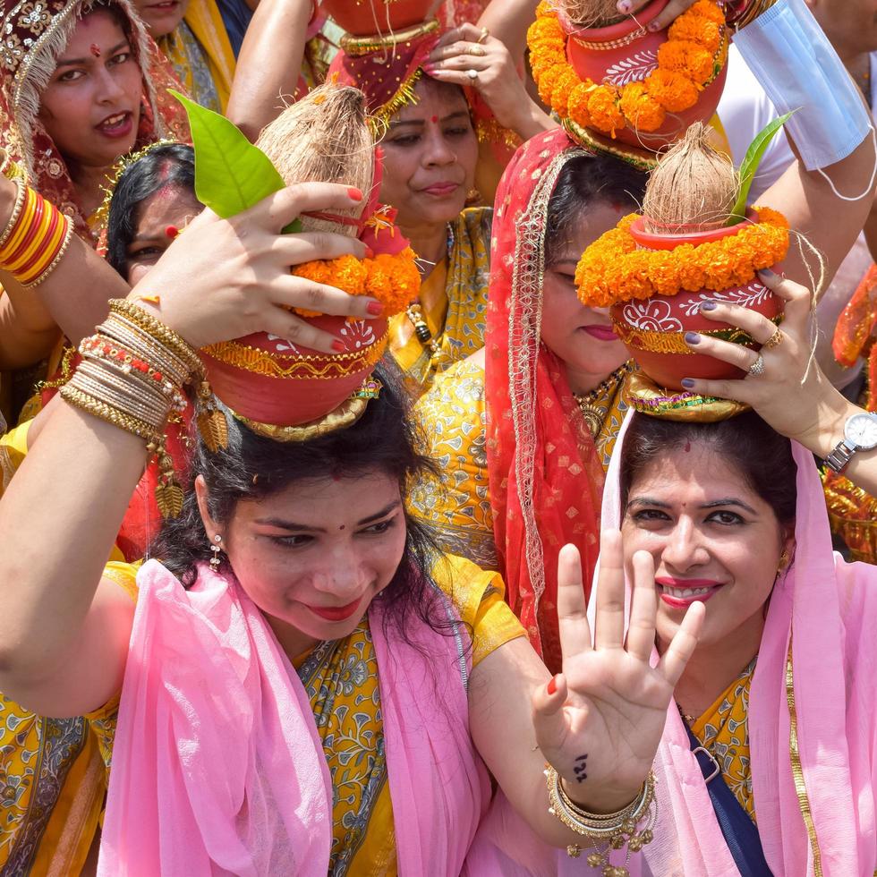 nueva delhi, india 03 de abril de 2022 - mujeres con kalash en la cabeza durante el templo jagannath mangal kalash yatra, devotos hindúes indios llevan ollas de barro que contienen agua sagrada con un coco encima foto