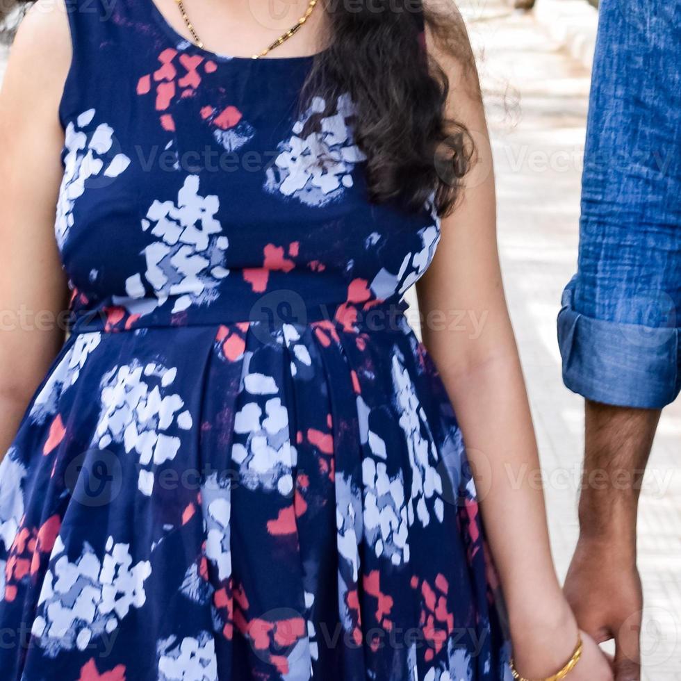 pareja india posando para una sesión de fotos de maternidad. la pareja está posando en un césped con hierba verde y la mujer está faluntando su panza en el jardín lodhi en nueva delhi, india